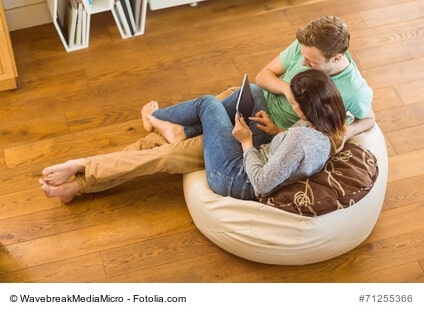 Cute couple using tablet pc on beanbag